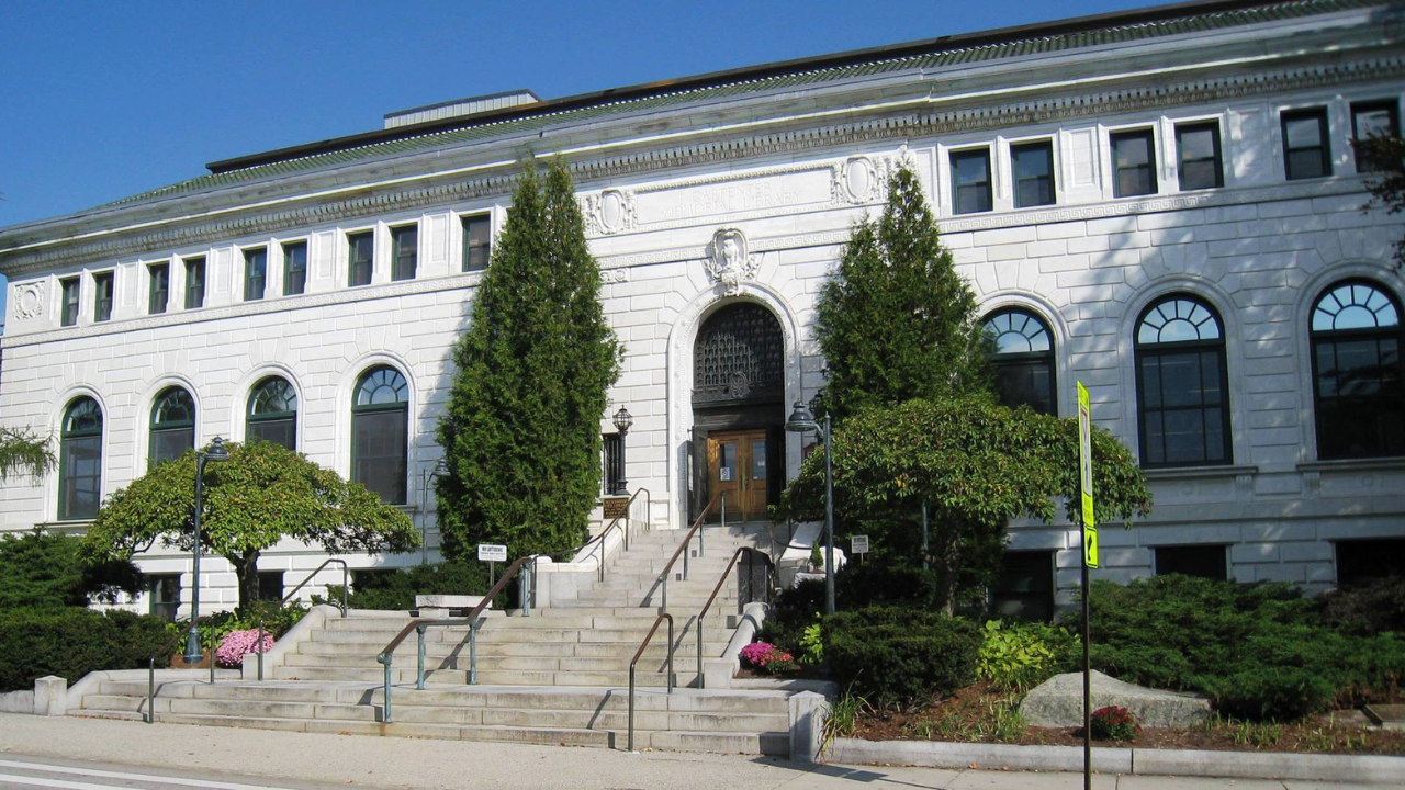 Outside of the Manchester Library with green trees lining the building