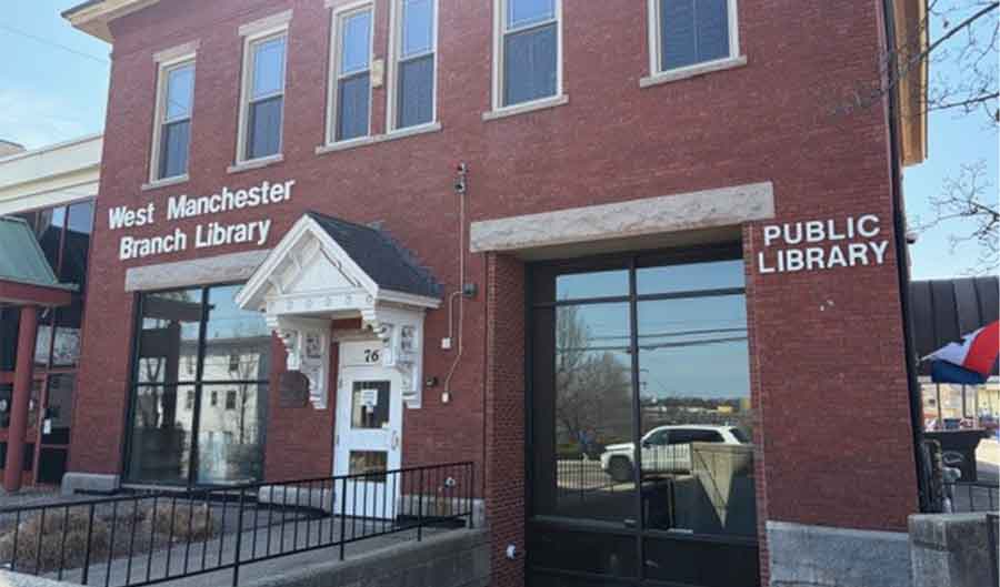 Manchester West Public Library Brick Building with a large door and window.
