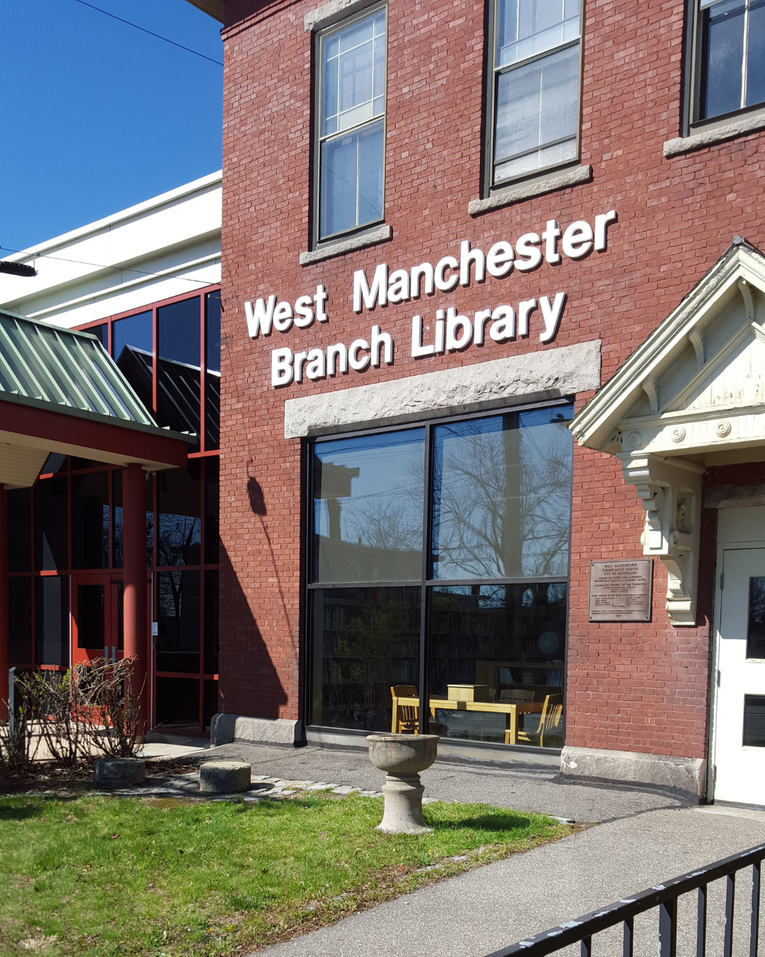 Exterior of the West Manchester Branch Library building with red brick facade and entrance on a sunny day.