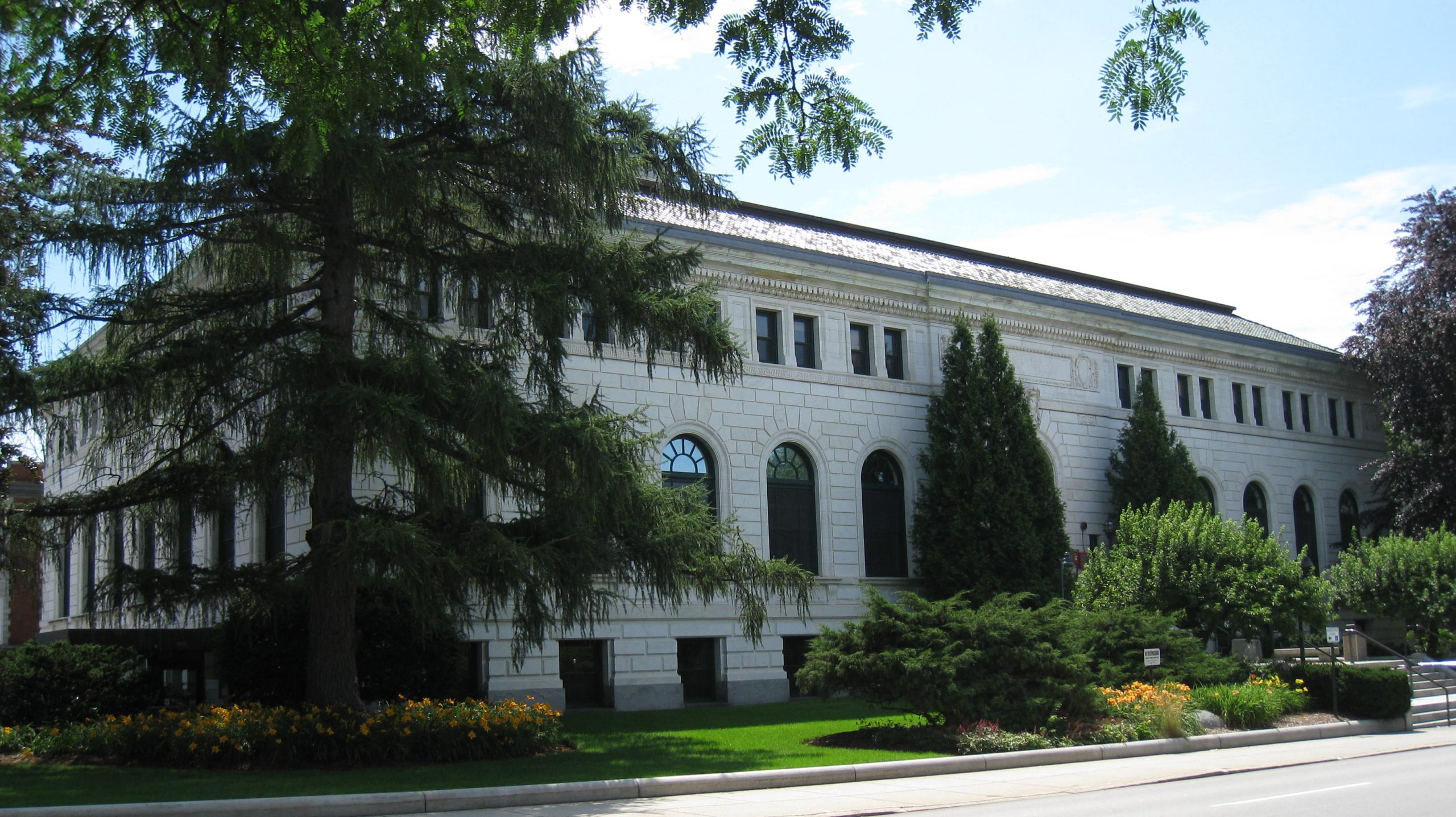 outside of the library - a two story building with tall trees lining the outside